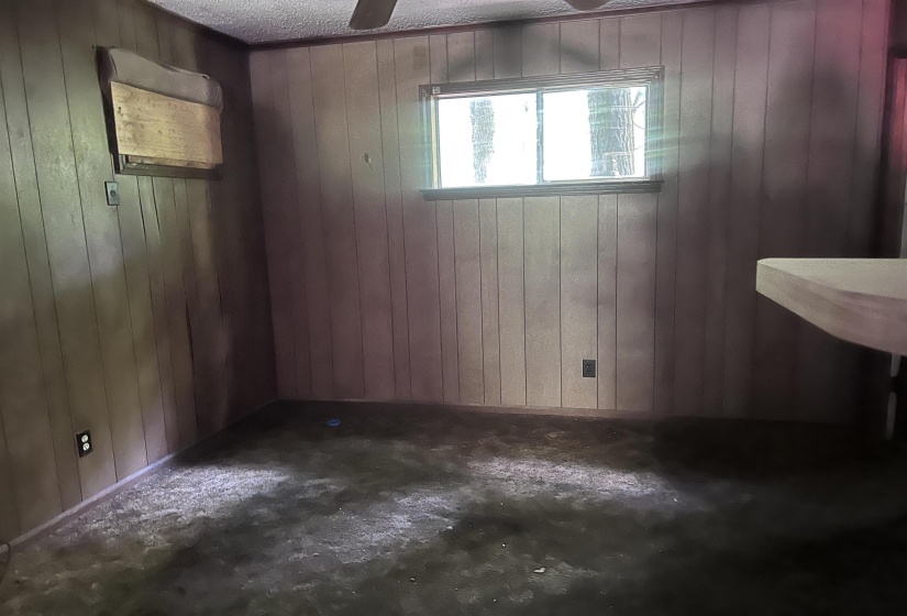 Room featuring wood-finish paneling, a single window, a ceiling fan.