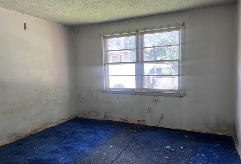 Room featuring a double-hung window with multiple panes, textured ceiling, light-colored walls, and blue carpeting