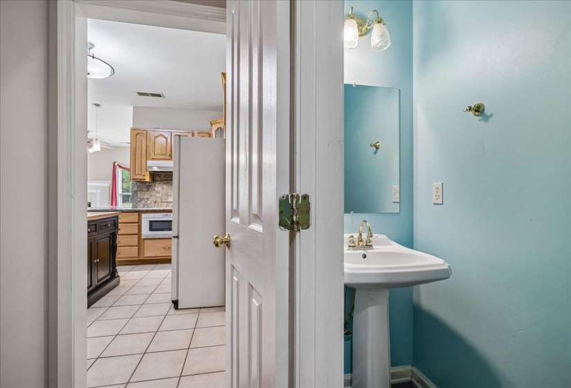 Pedestal sink with wall-mounted mirror and sconce lighting