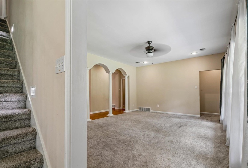 Carpeted living area featuring a ceiling fan with a medallion, recessed lighting, and a window with drapes
