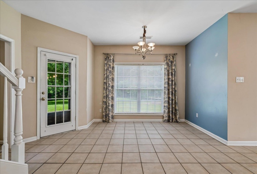 Spacious room featuring tile flooring, a multi-pane glass door, and a large window with blinds