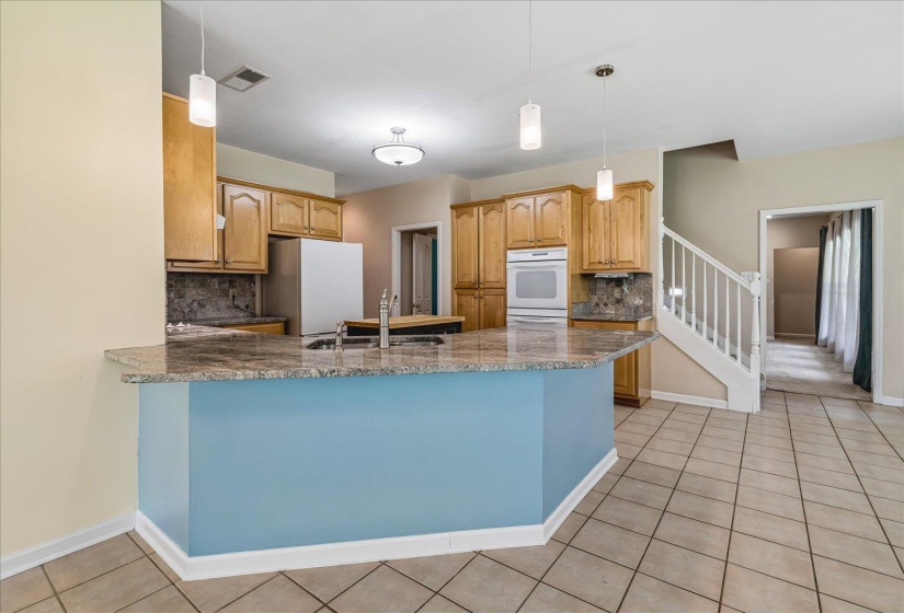 Kitchen featuring a large central island with a sink, light wood cabinetry, and granite countertops