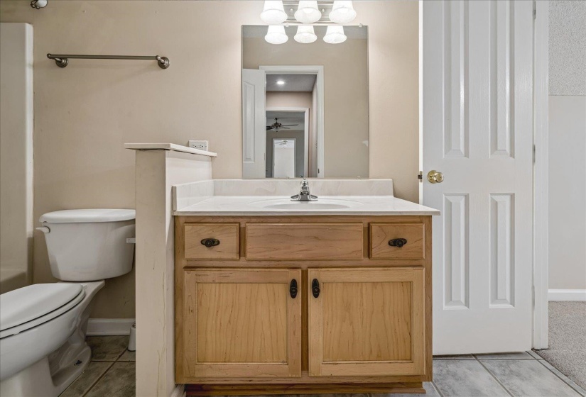 Bathroom featuring a wood-finish vanity with a white countertop, an integrated sink, and an overhead vanity light