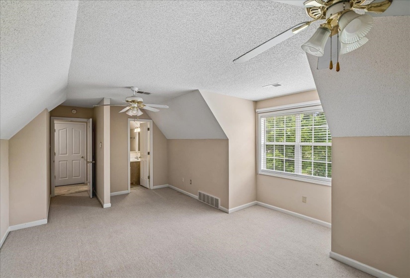 Spacious room with sloped ceilings and light beige wall paint