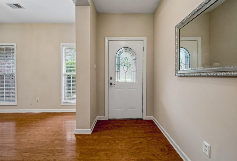 Entryway featuring a white door with decorative glass, wood-finish flooring, and neutral wall tones