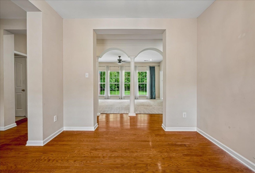 Warm wood-finish flooring extending into an arched entryway