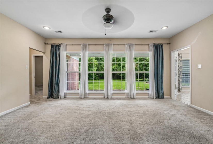 Bright living space featuring expansive windows, neutral wall tones, textured carpeting, a ceiling fan, and recessed lighting