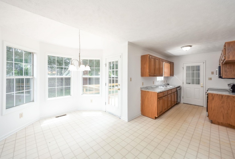 Kitchen and dining area featuring light wood cabinetry, stone-finish countertops, and a white tile-patterned floor