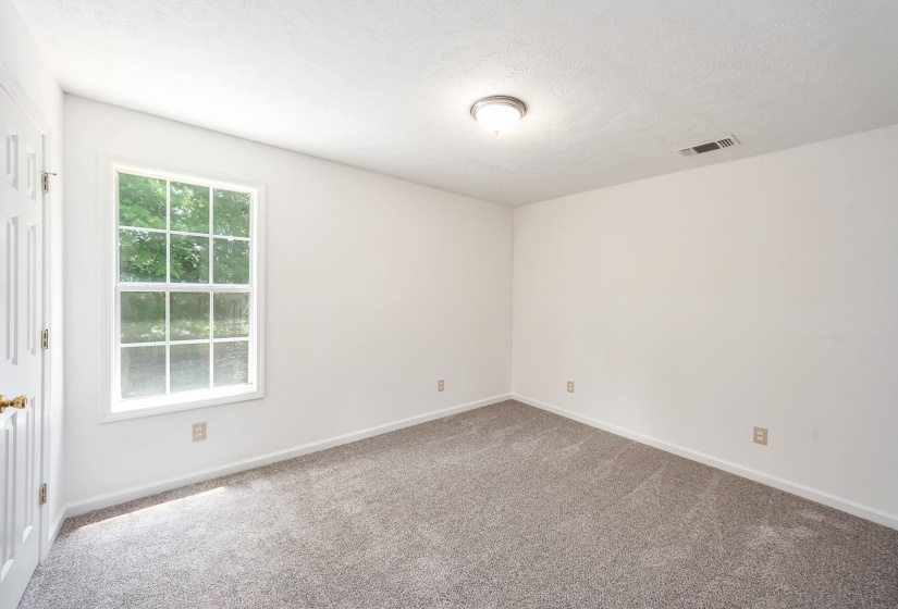 Room featuring a multi-pane window, neutral wall paint, textured ceiling, and gray carpet flooring