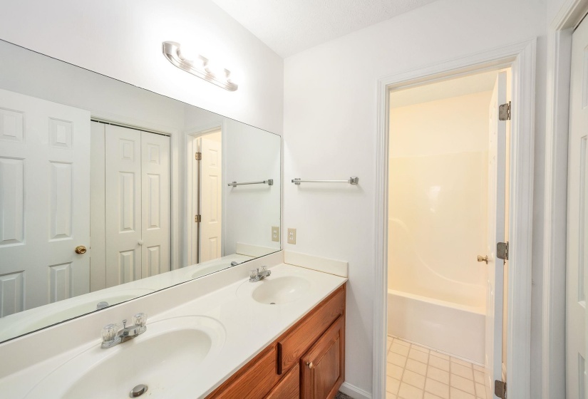Dual vanity with integrated sinks, wood-finish cabinetry, and a full-width mirror