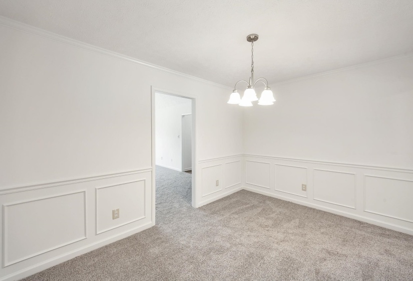 Interior room featuring wainscoting, crown molding, a brushed nickel chandelier, and gray carpeting