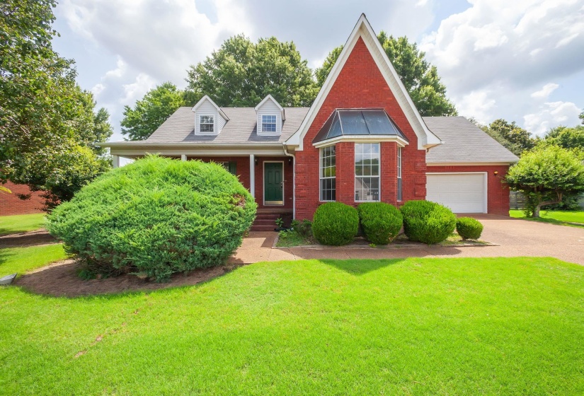 Red brick exterior with a prominent bay window, attached garage, and dormer windows