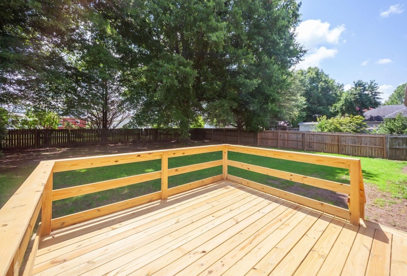 Expansive wood deck with natural wood railing overlooking a grassy backyard