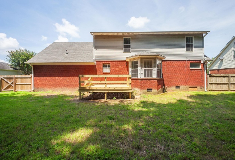 Expansive backyard featuring a manicured lawn, a new wood deck, and wood privacy fencing