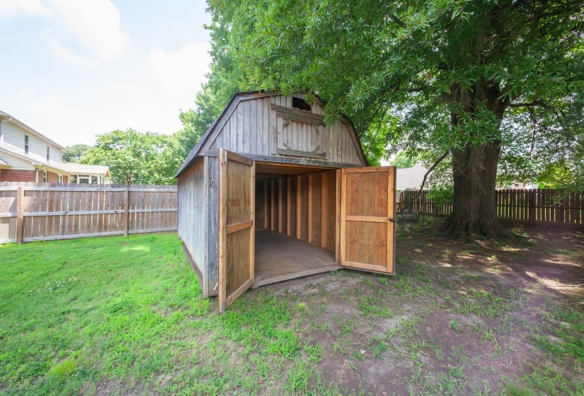 Wood-sided storage shed with a gambrel roof and double barn doors