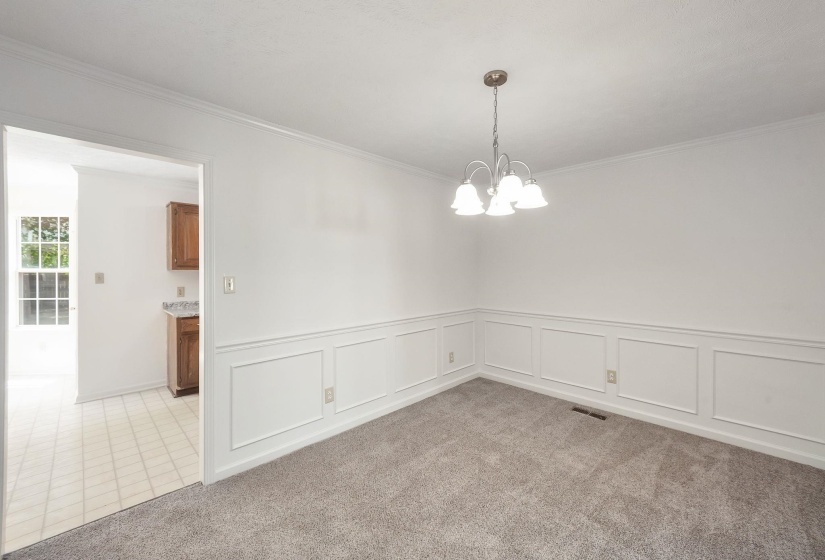 Dining area featuring wainscoting, crown molding, and a four-light chandelier