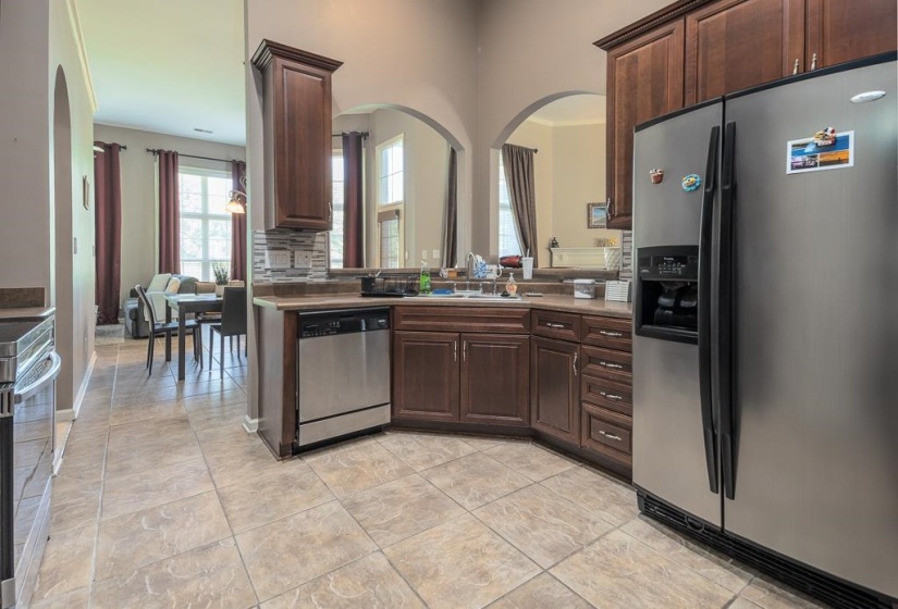 Kitchen featuring stainless steel appliances, dark wood-finish cabinetry, tile flooring, and arched doorways