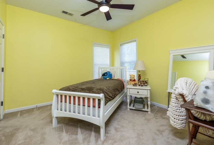 Bedroom featuring light yellow walls, neutral carpeting, and a ceiling fan with integrated lighting