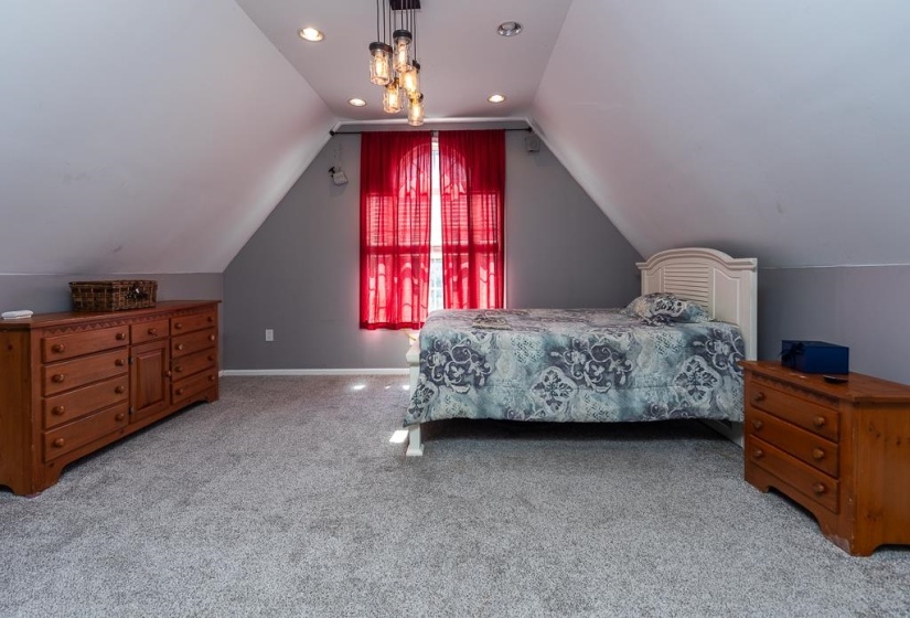 Carpeted room featuring a sloped ceiling, recessed lighting, and a multi-bulb chandelier