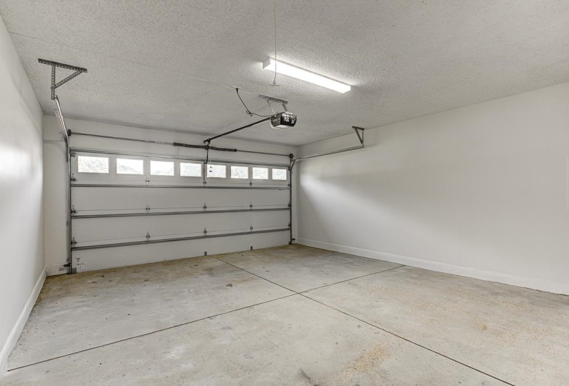 Spacious garage featuring a concrete floor, white walls, and a white paneled overhead door with frosted window inserts