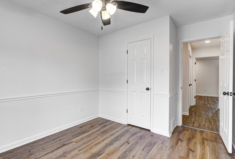 Room featuring wood-finish flooring, white walls with chair rail molding, and a ceiling fan with integrated lighting