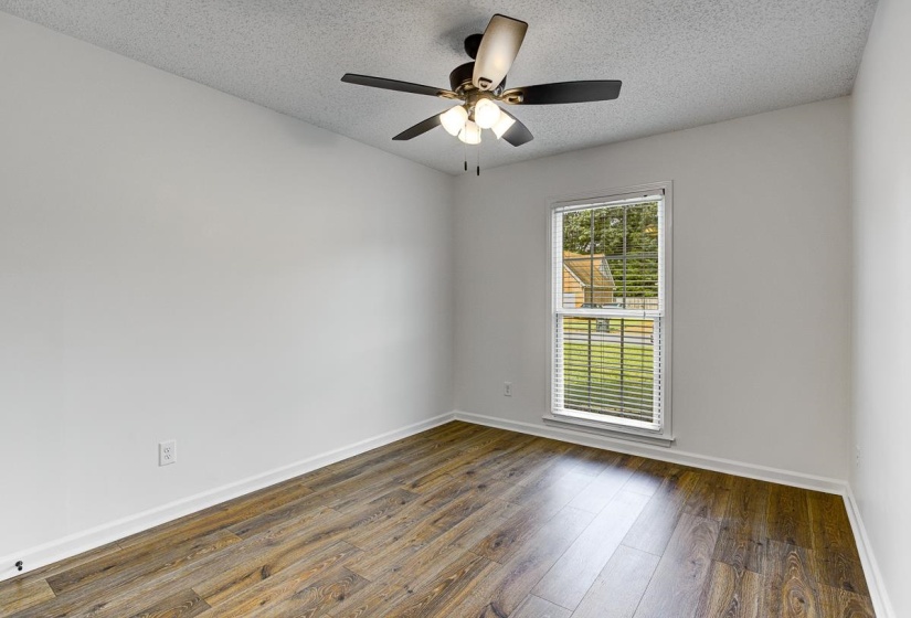 Room featuring wood-finish flooring, white baseboards, a ceiling fan with light fixture, and a window with blinds