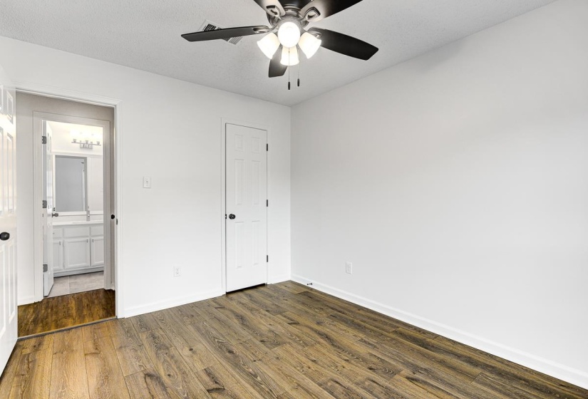 Spacious room featuring wood-finish flooring, crisp white walls, and a contemporary ceiling fan with integrated lighting