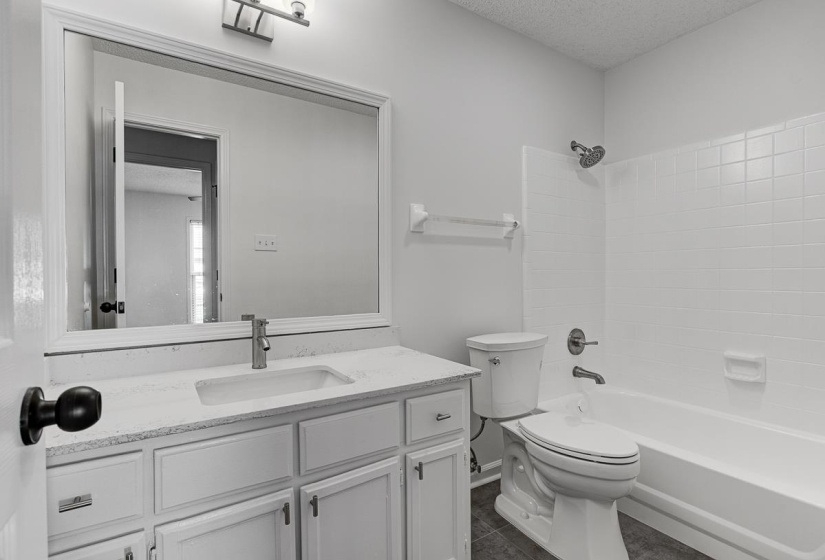 Bathroom featuring a white vanity with an undermount sink, a white countertop, and a framed mirror