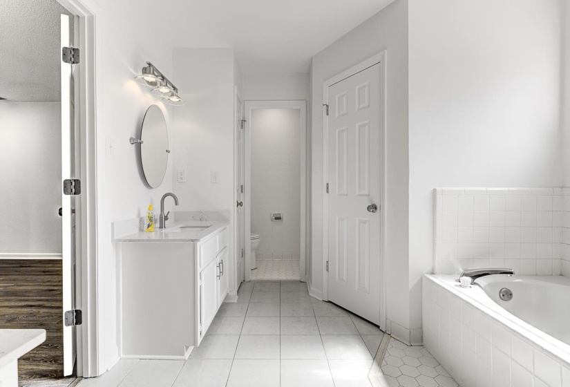 Bathroom featuring a white vanity with a stone countertop, an oval mirror, and a three-light fixture