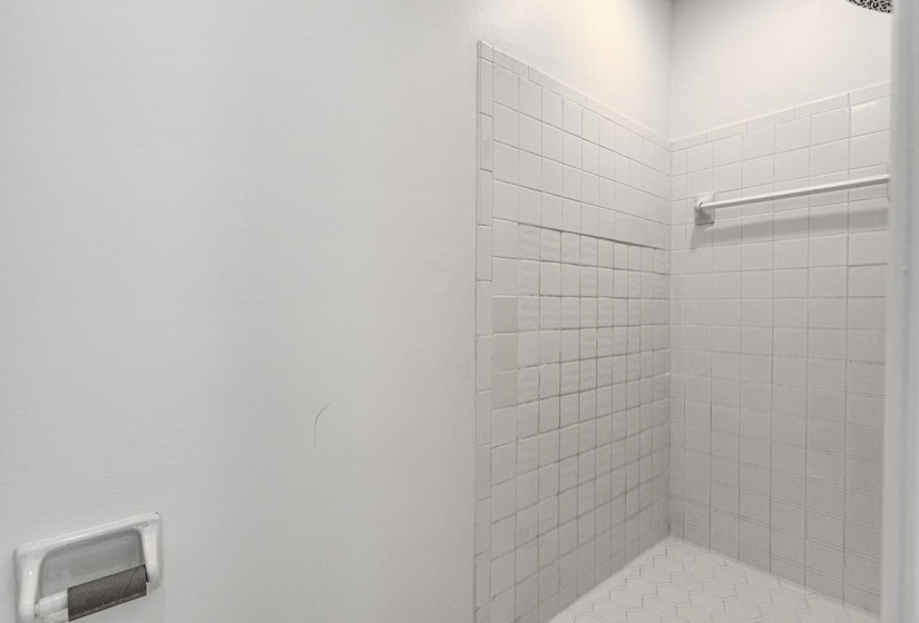 White tiled shower with a built-in niche and hexagonal tile flooring