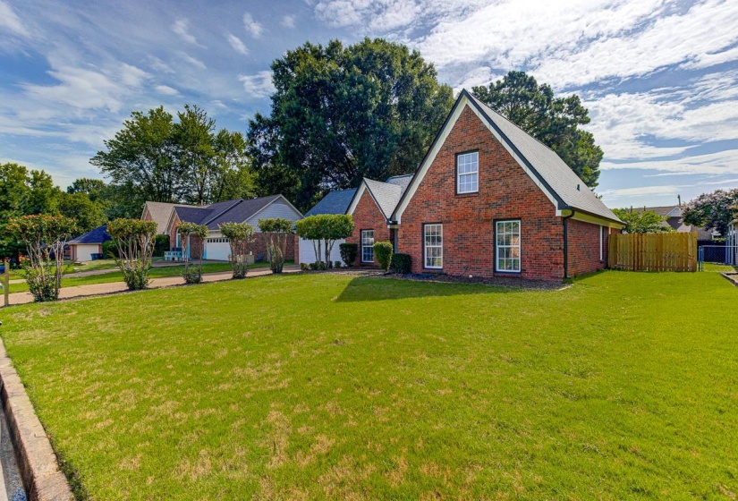 Brick exterior with a gabled roofline, featuring white window frames and a spacious front lawn