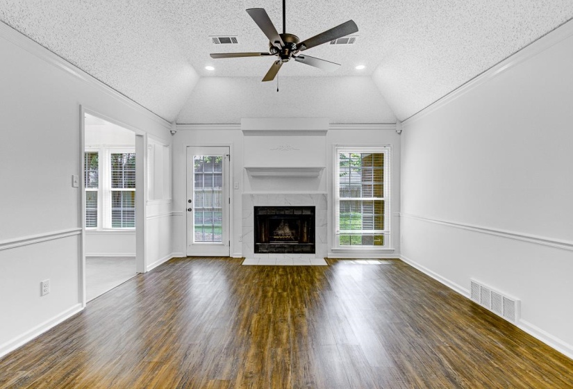 Spacious room featuring wood-finish flooring, a vaulted ceiling, and recessed lighting