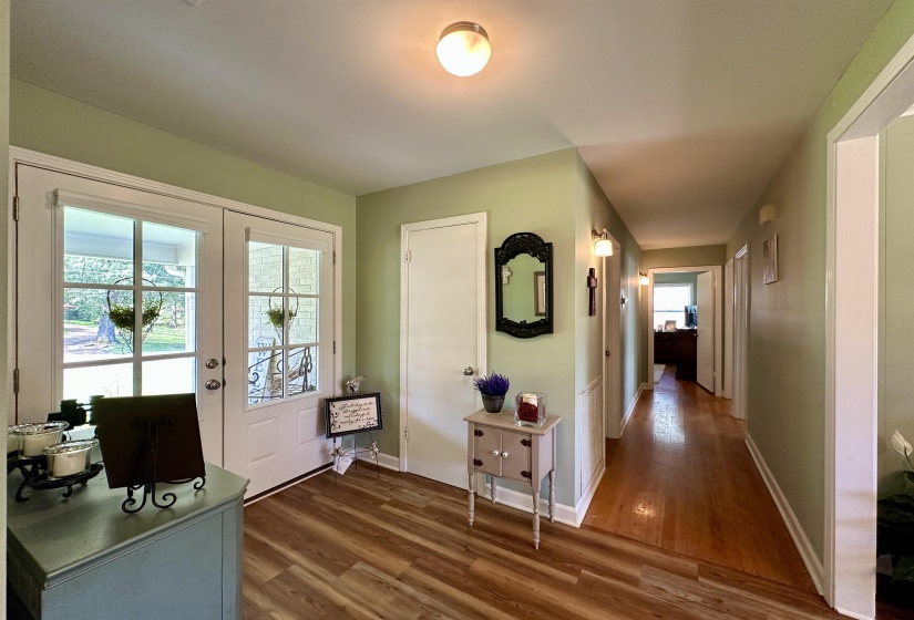 Entryway featuring dual glass-paneled doors, wood-finish flooring, and a hallway with hardwood flooring