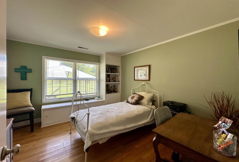 Room featuring wood-finish flooring, a double window with a window seat, and built-in shelving