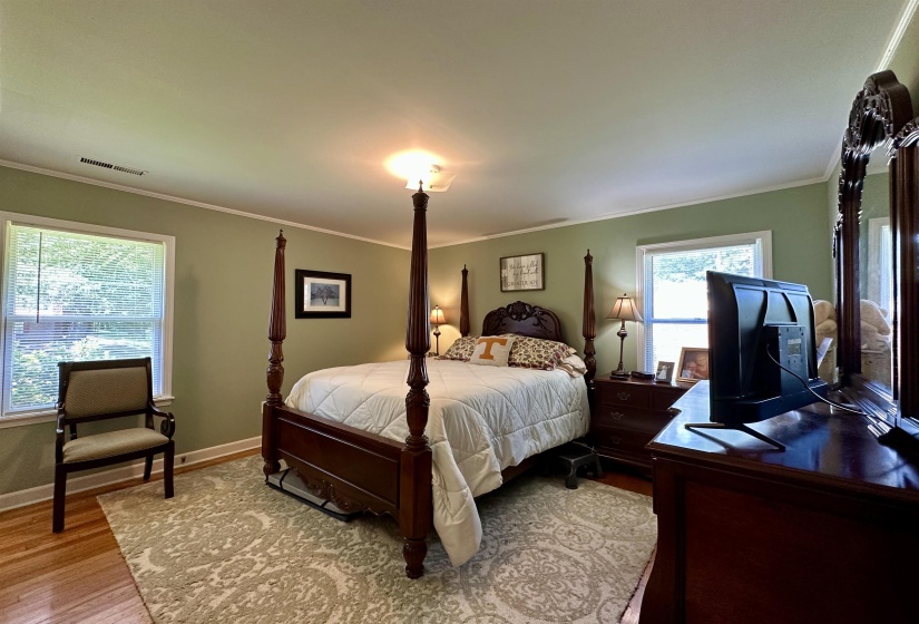 Bedroom with light green walls, hardwood flooring, and white trim