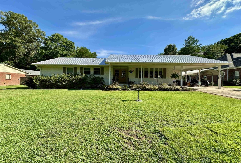 Ranch-style residence featuring a metal roof, white brick facade, and an integrated carport