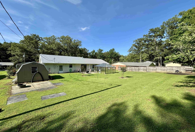 Expansive backyard featuring a manicured lawn, a detached storage shed, and a privacy fence