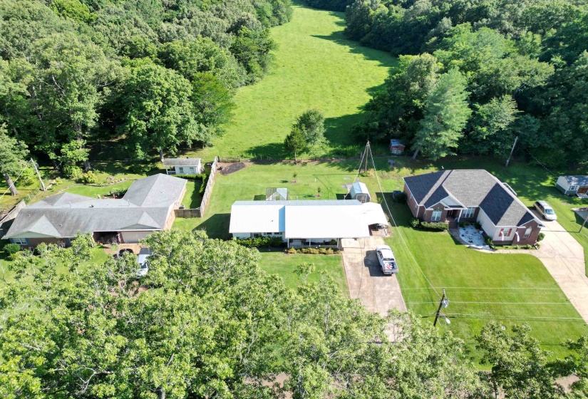 Spacious property featuring a brick and siding exterior, an extended concrete driveway, a well-maintained front lawn, and mature trees