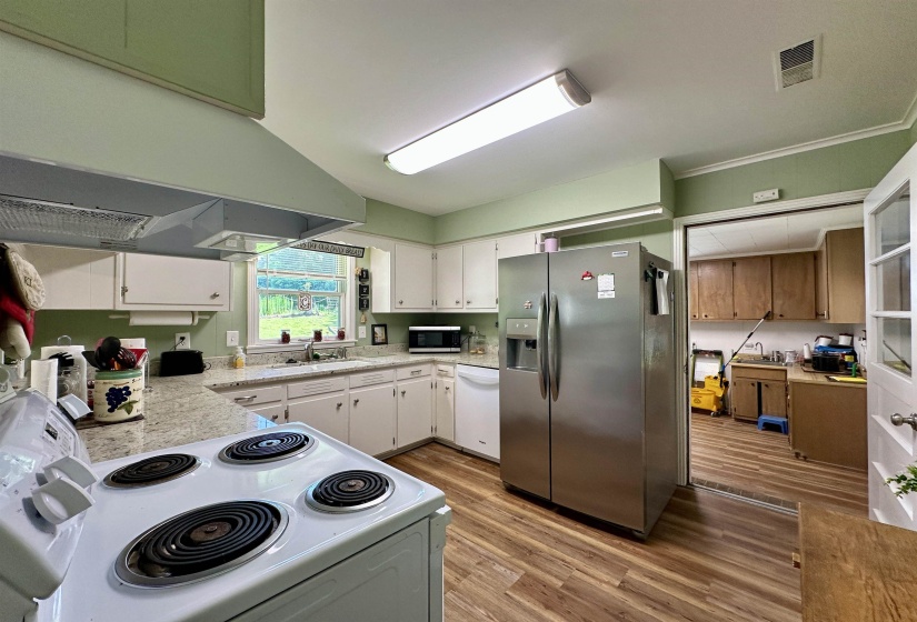 Kitchen featuring wood-finish flooring, white cabinetry, and light-colored countertops