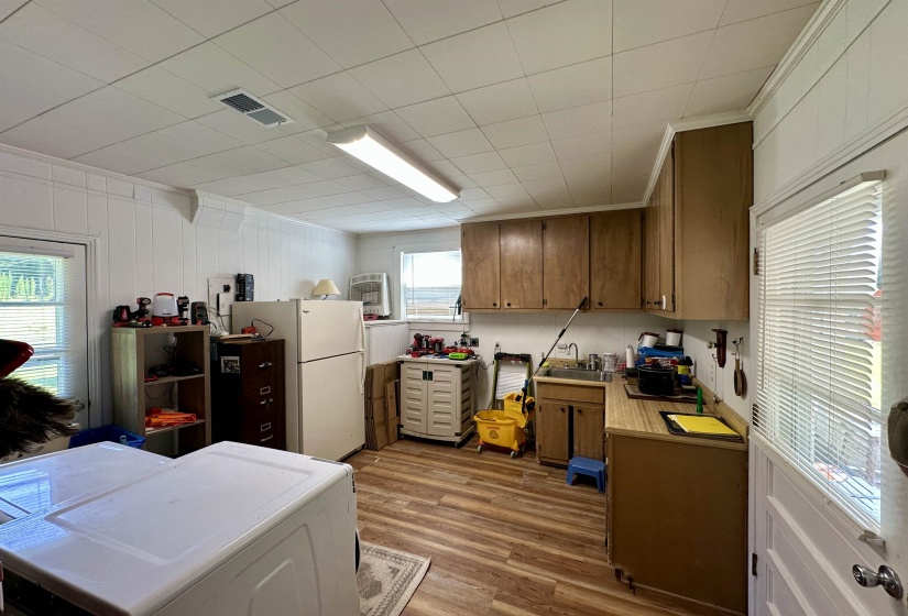 Utility room featuring wood-finish flooring, white panel walls, and a drop ceiling