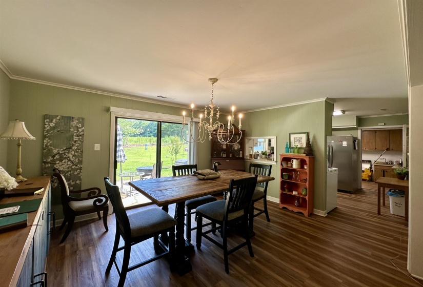Spacious dining area featuring wood-finish flooring, a decorative chandelier, and light green wall paneling