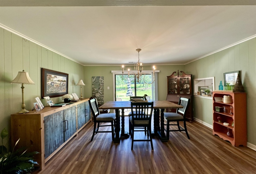 Dining area featuring wood-finish flooring, vertical panel wall accents, and an overhead chandelier