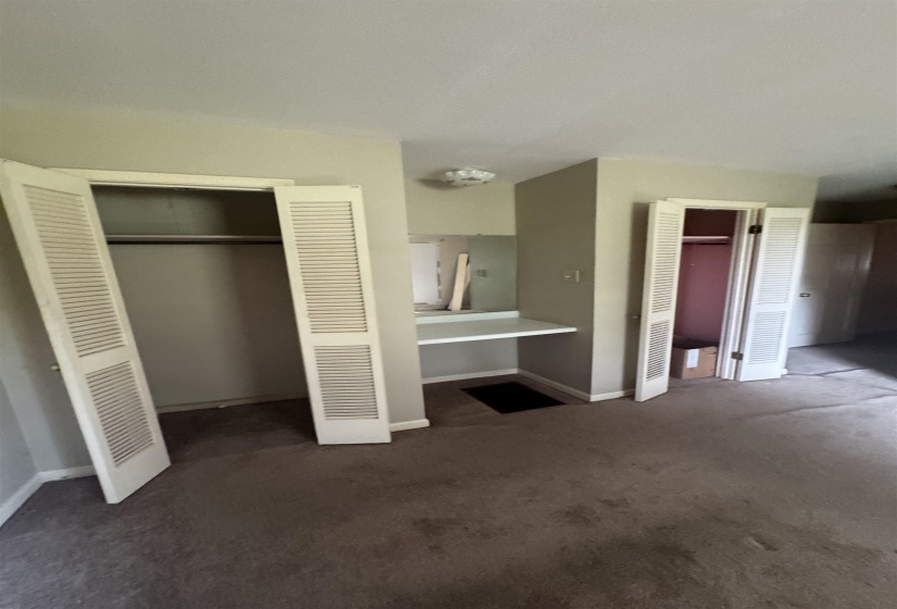 Room featuring two louvered bifold door closets and a built-in vanity with a mirror