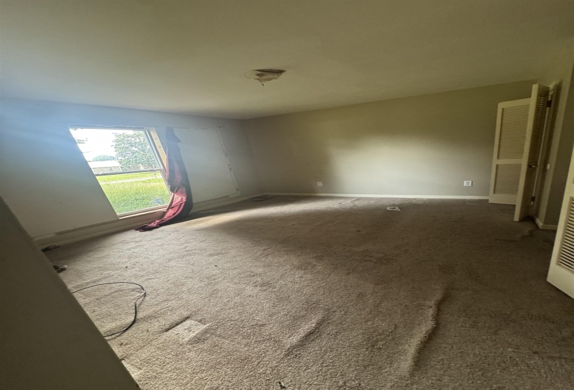 Room with beige carpeting, a single window, and a ceiling-mounted light fixture