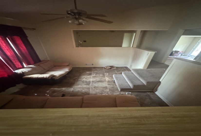 Living area featuring a ceiling fan with integrated lighting, wood-finish flooring, and a half-wall partition