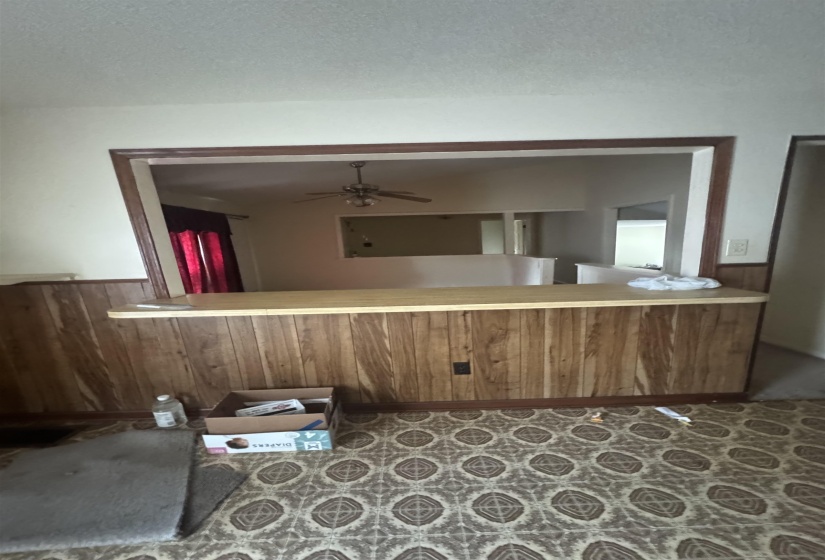 Pass-through window with wood-finish trim, wood-paneled half-wall, and a light-toned countertop