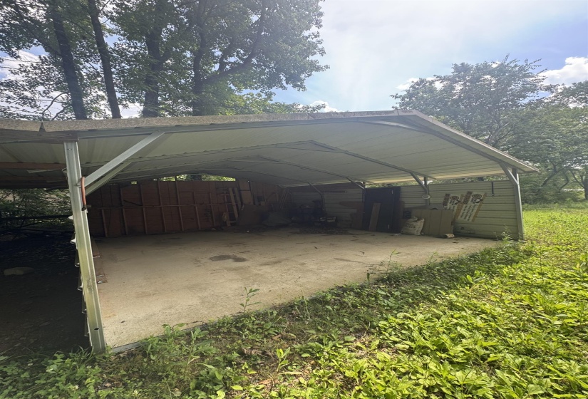 Metal carport structure with a concrete pad and partial perimeter siding