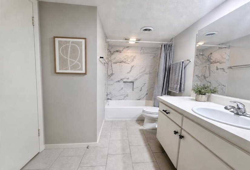 Guest Bathroom featuring a white vanity with an integrated sink, a large wall-mounted mirror, and tile flooring