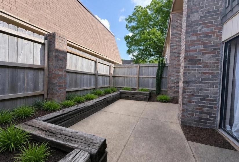 Private outdoor patio featuring a concrete surface, perimeter fencing, and raised planting beds