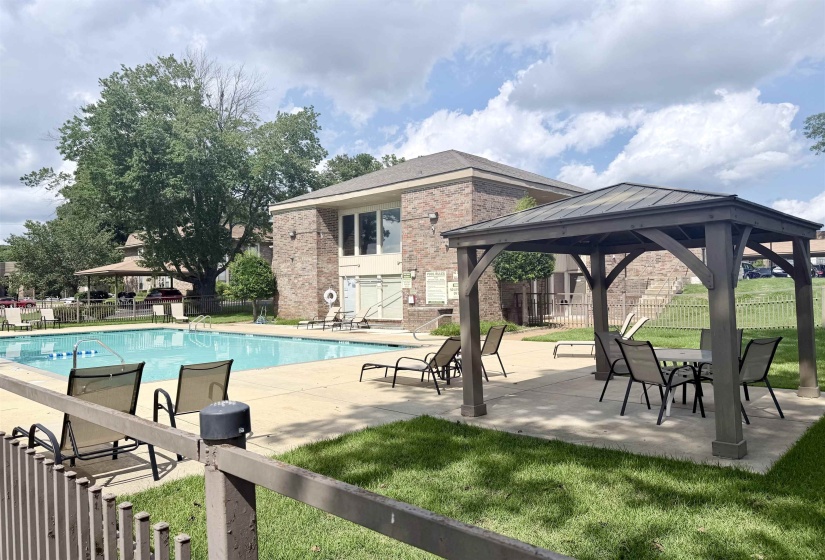 Community swimming pool with surrounding concrete deck, wooden gazebo